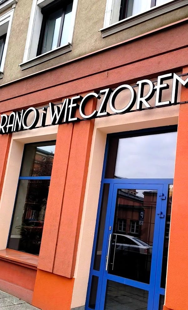 Front lokalu — neon „RANO i WIECZOREM” na pomarańczowej fasadzie